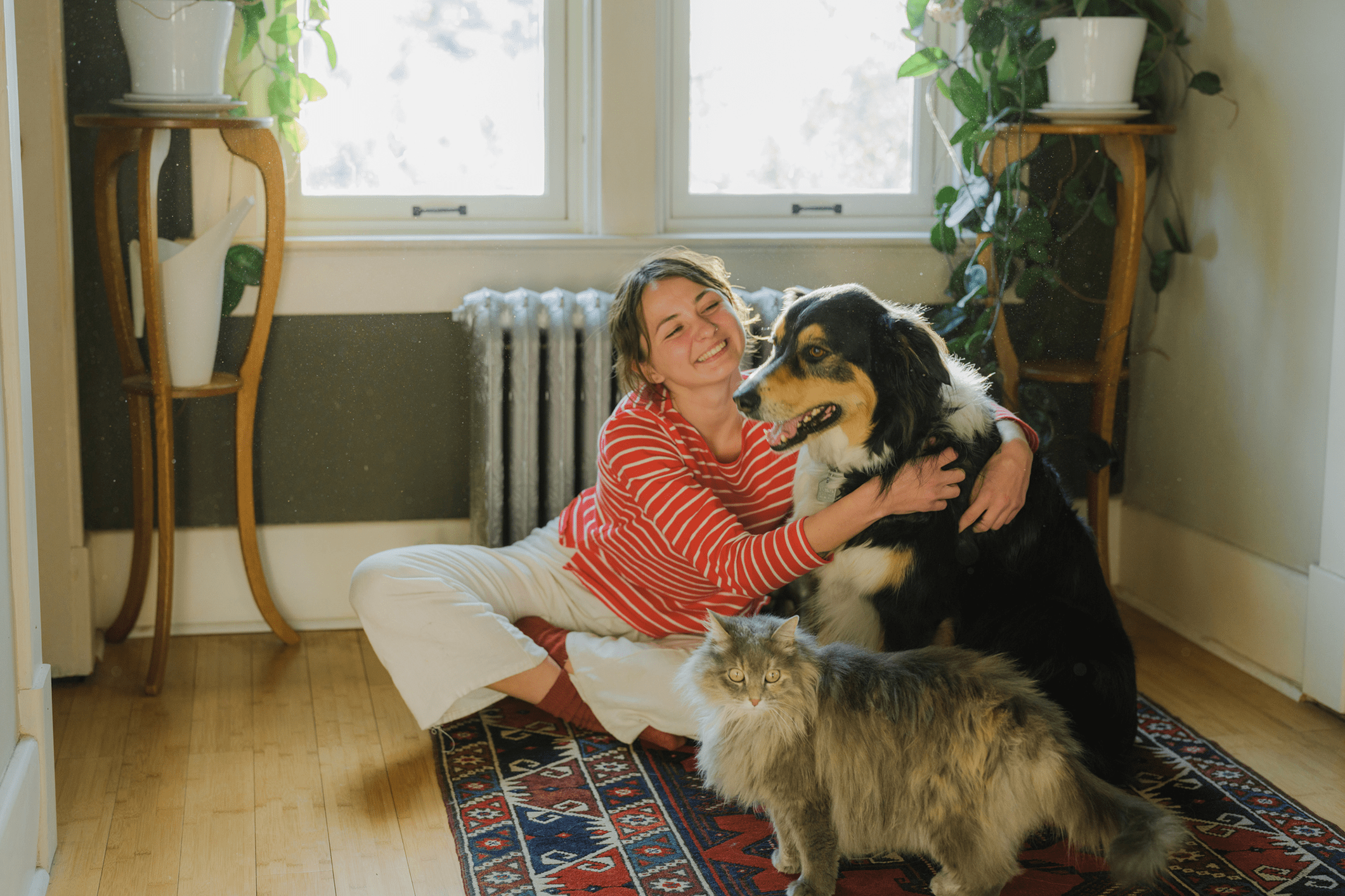 Woman with dog and cat indoors, smiling.