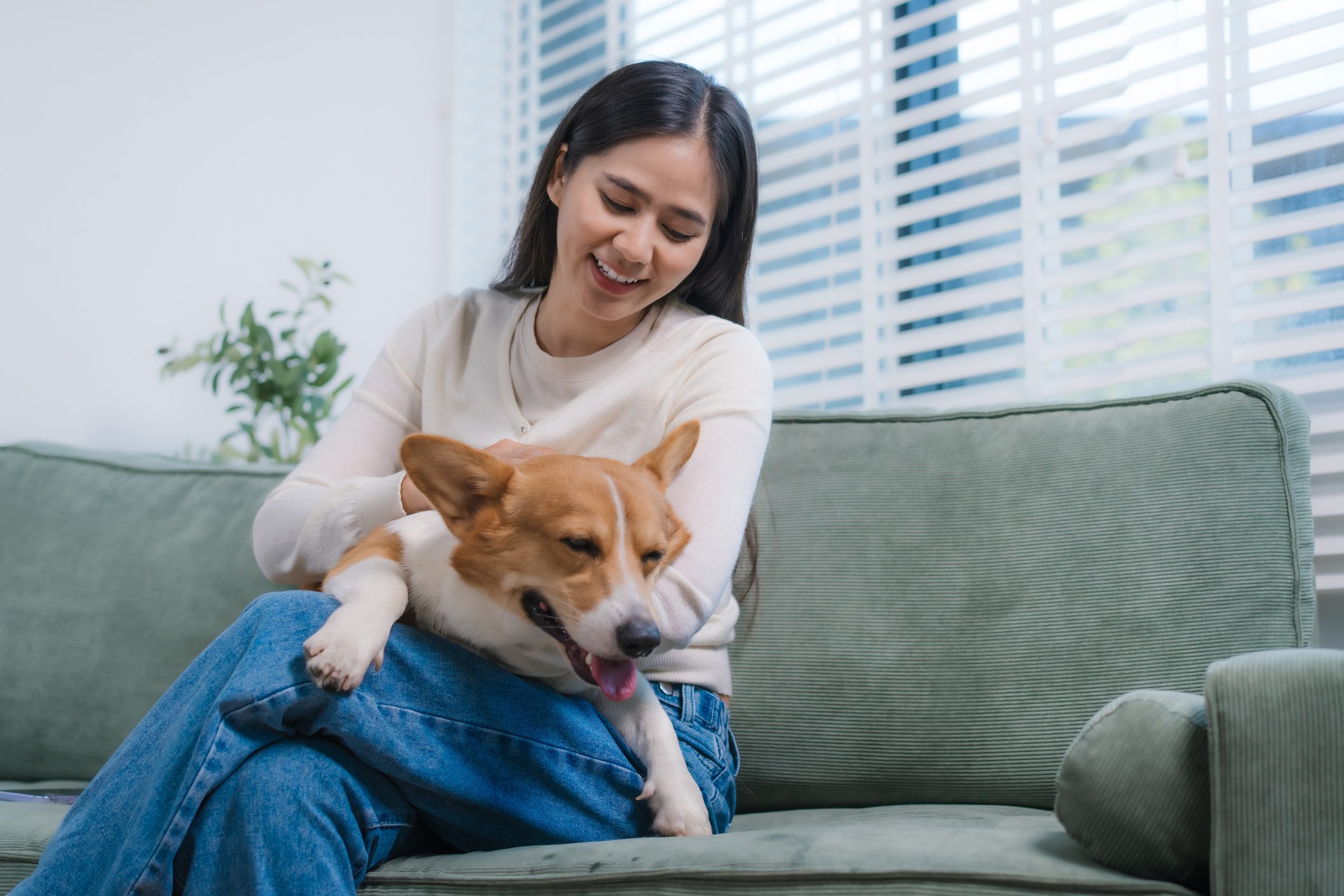 Woman smiling with dog on couch.
